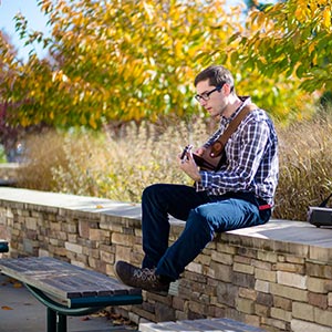 Male student playing guitar outdoors