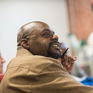 Man in brown shirt holding pen