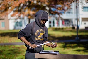 Student drumming on a notebook outside in the fall
