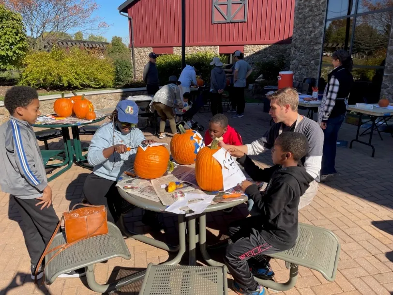 a group of people sitting around a table with pumpkins