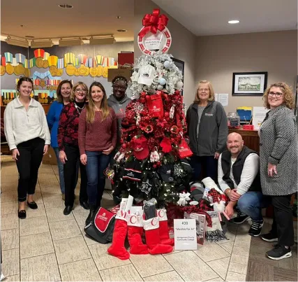 a group of people standing around a Christmas tree