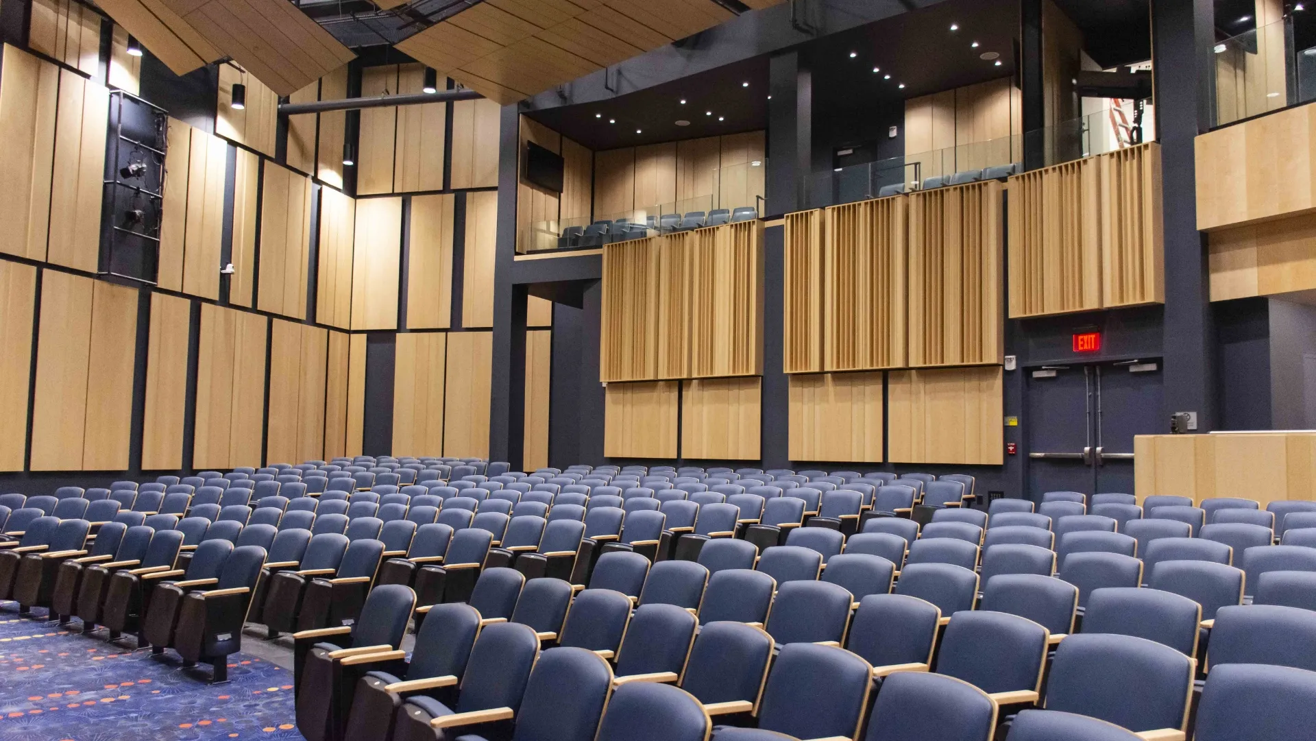 a large auditorium with rows of blue chairs