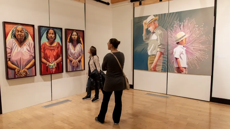 a group of people standing in front of paintings