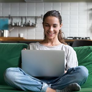 Women sitting on green couch with laptop open