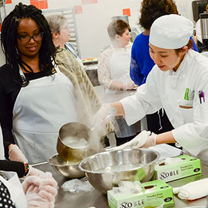 Women and chef looking over food preparations