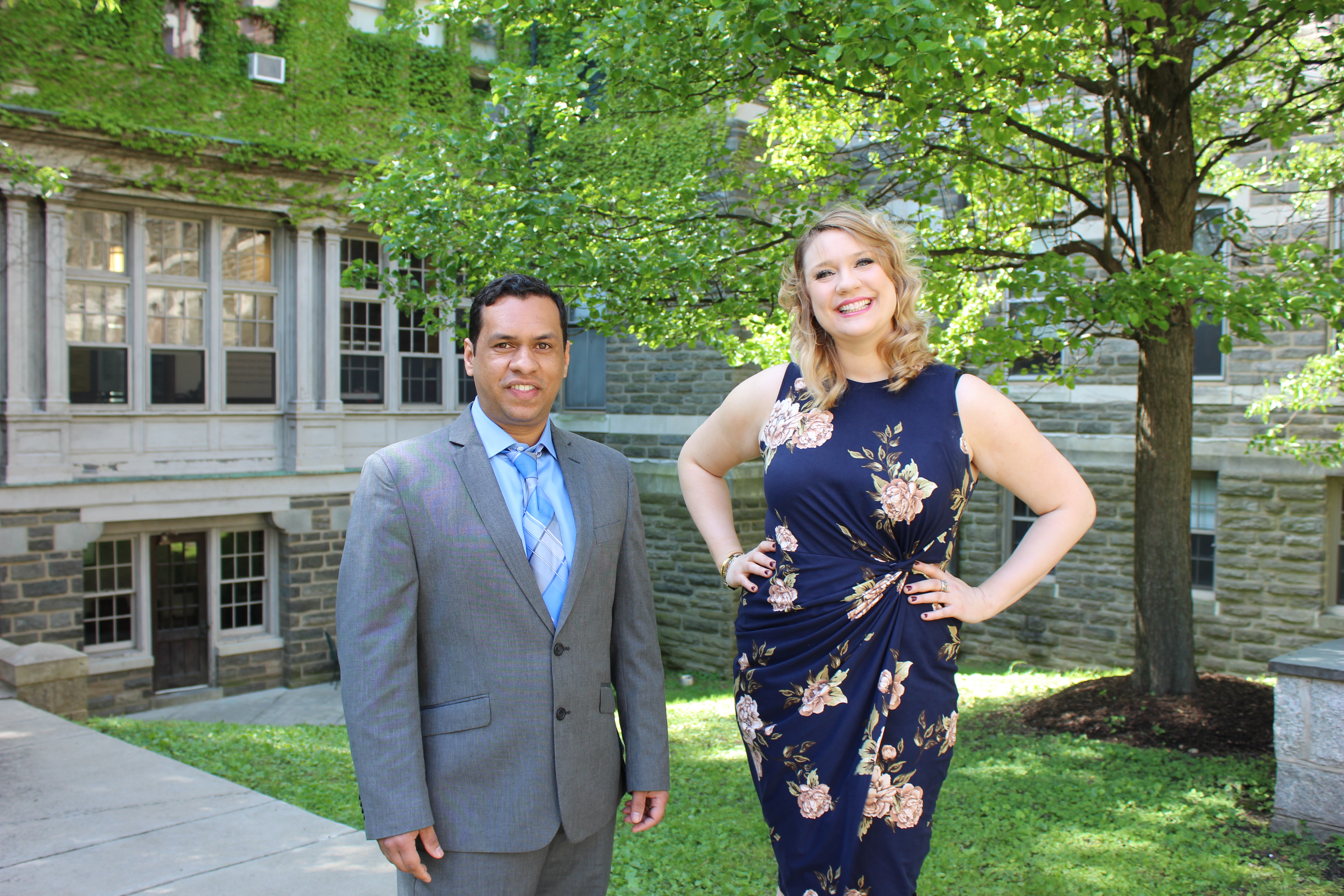 Man in suit and woman in pose in front of campus buildilng