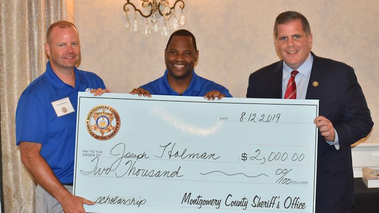 MCSO Deputy Chief Adam Berry, left, and Sheriff Sean Kilkenny, right, present Deputy Joseph Holman, center, with the first check awarded from the Sheriff's Scholarship Fund, Monday, Aug. 12, 2019.