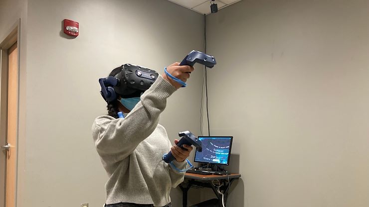 Radiography student Christie Biswas wears virtual reality technology to practice taking an X-ray on a patient. Photo by Eric Devlin.