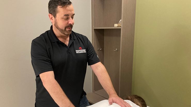 Massage Therapy Program Manager Bill Mullen massages a client on a table inside the Massage Therapy Clinic in the Health Sciences Center. The program celebrates its fifth anniversary this year. Photo by Eric Devlin.