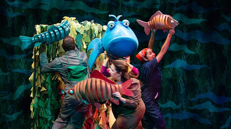 Emmanuel Elpenord, Kelly Grago, Leanne Brunn, Mukta Phatak in a performance of “The Pout-Pout Fish.” Each actor is holding a brightly colored fish puppet. 