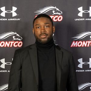 Mustangs Men's Basketball Head Coach Koran Prince portrait in front of a black Montco background
