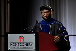 Dr. Matthew Riddick, '08, Chair of the MCCC Alumni Board of Directors, speaks at a lectern during Commencement