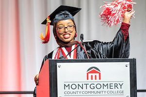 Commencement student speaker Loujain Ahmed holds a pom-pom in the air during her speech at Commencement