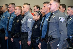 A group of Municipal Police Academy cadets stand at attention during a graduation ceremony.