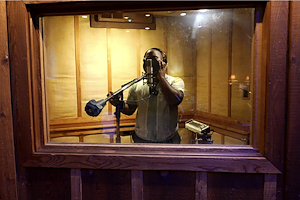 Shaun Brown sings into a microphone in a recording booth