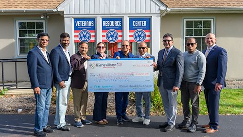 A group of people stand with a large check for $5,000 in front of a building with Veterans Resource Center written on it.