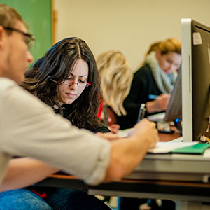 Student writing in front of computer screen