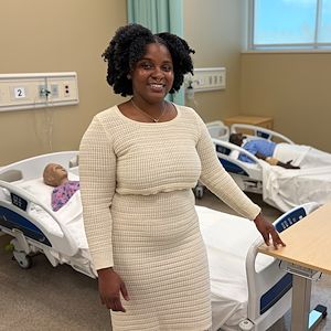 Anthonesha Anguin stands in the Nursing Clinic Lab inside the Health Sciences Center. Dummy patients are in beds behind her.   