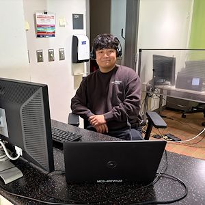Joshua Jang sits at the Help Desk in the IT Services suite