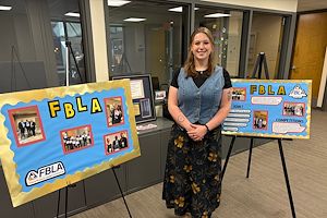 Sloane Harker stands with FBLA posters in a lobby