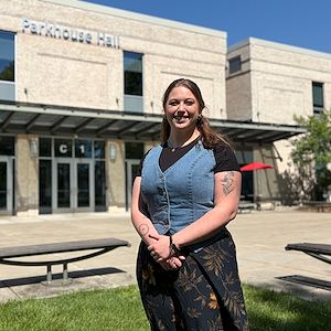 Sloane Harker smiles outside Parkhouse Hall on the Blue Bell Campus