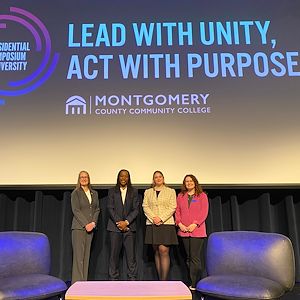 Sloane Harker stands with Dr. Omekongo, Dr. Vicki Bastecki-Perez, and Katie Esmaili at the Presidential Symposium panel. A screen above them says "Lead with unity. Act with purpose." 
